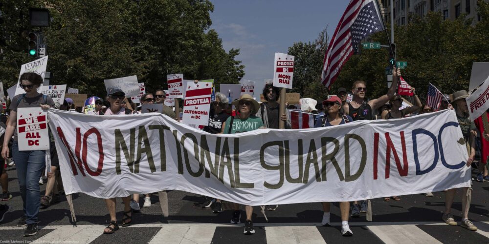 Demonstrators march in Washington, DC carrying a banner that reads " NO NATIONAL GUARD IN DC".