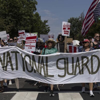 Demonstrators march in Washington, DC carrying a banner that reads " NO NATIONAL GUARD IN DC".