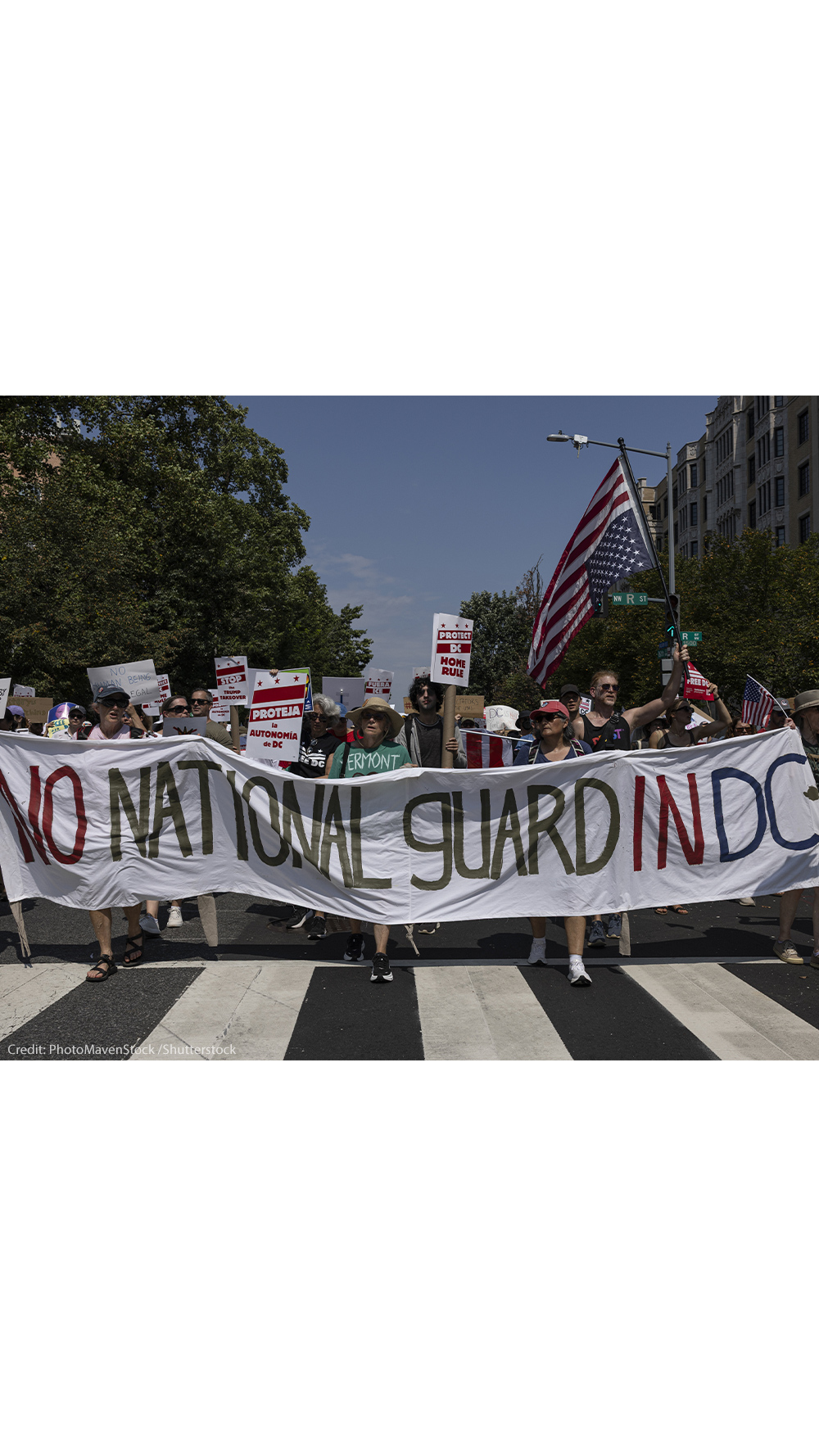 Demonstrators march in Washington, DC carrying a banner that reads " NO NATIONAL GUARD IN DC".