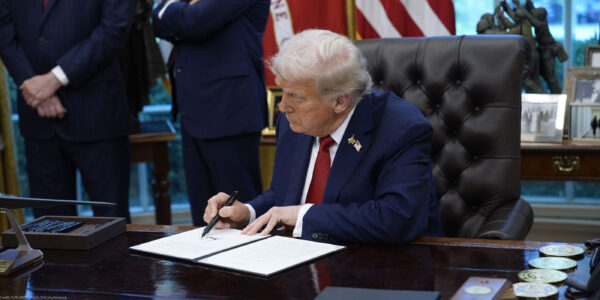President Trump signs an executive order in the Oval Office of the White House.
