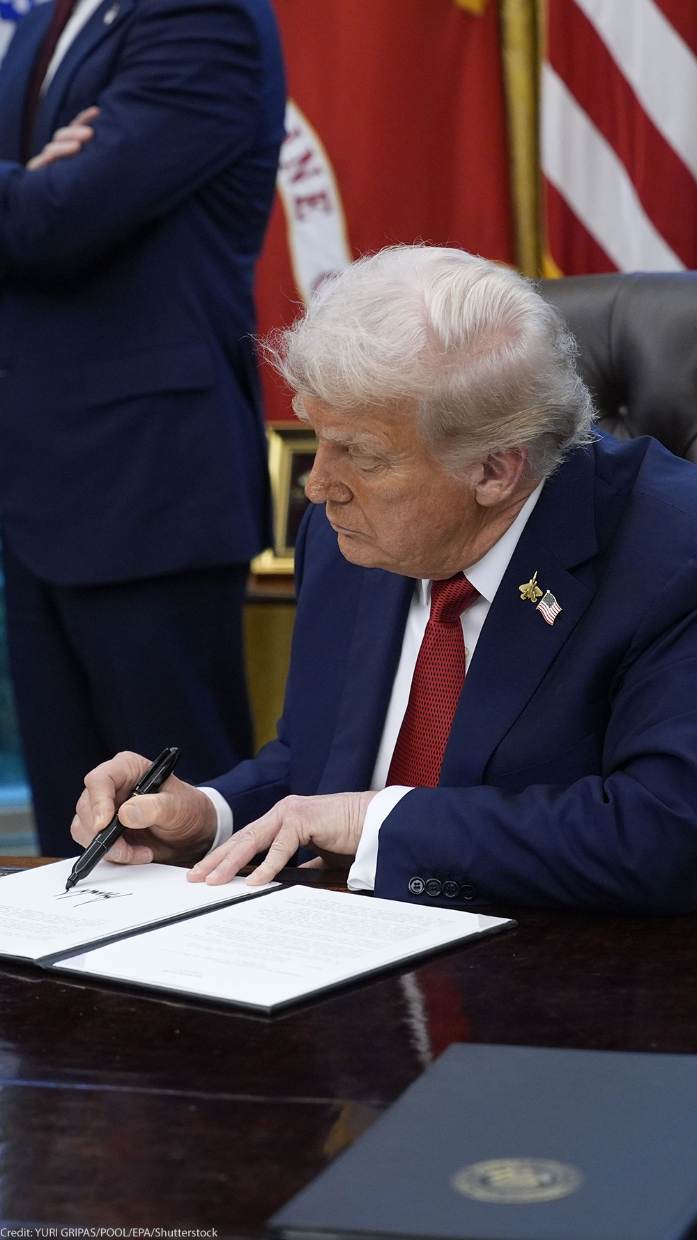 President Trump signs an executive order in the Oval Office of the White House.