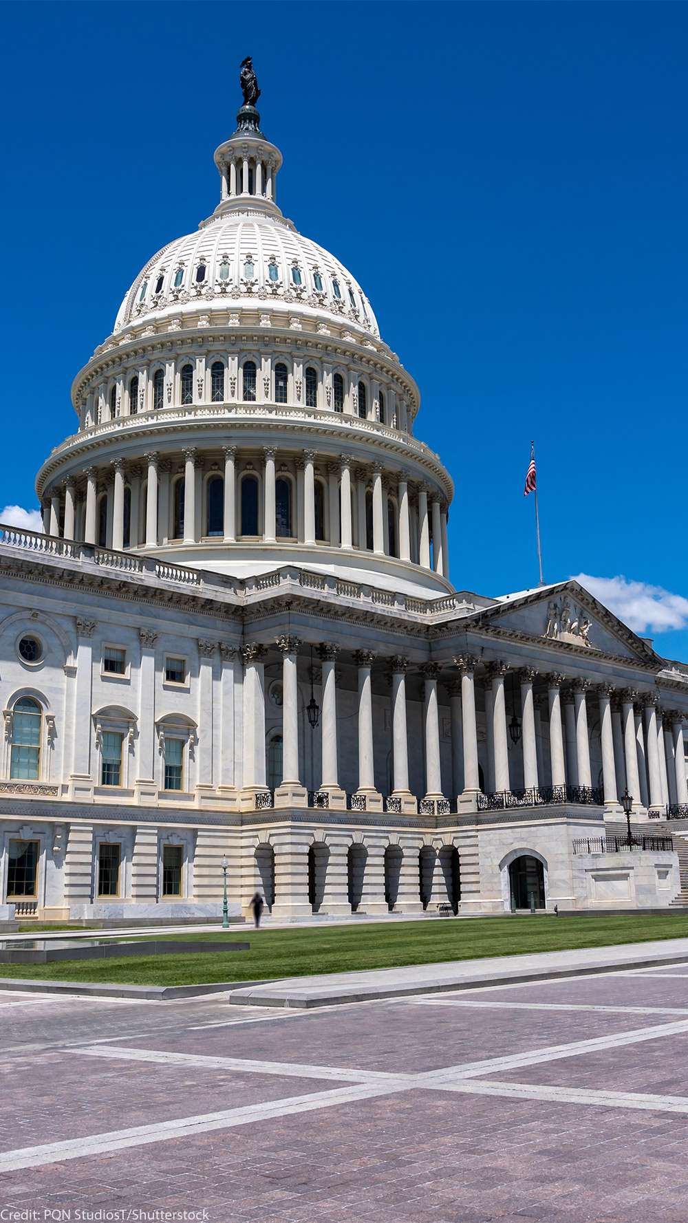 Wide daytime view of the U.S. Capitol building in Washington, D.C., with the white dome and columns under a bright blue sky.